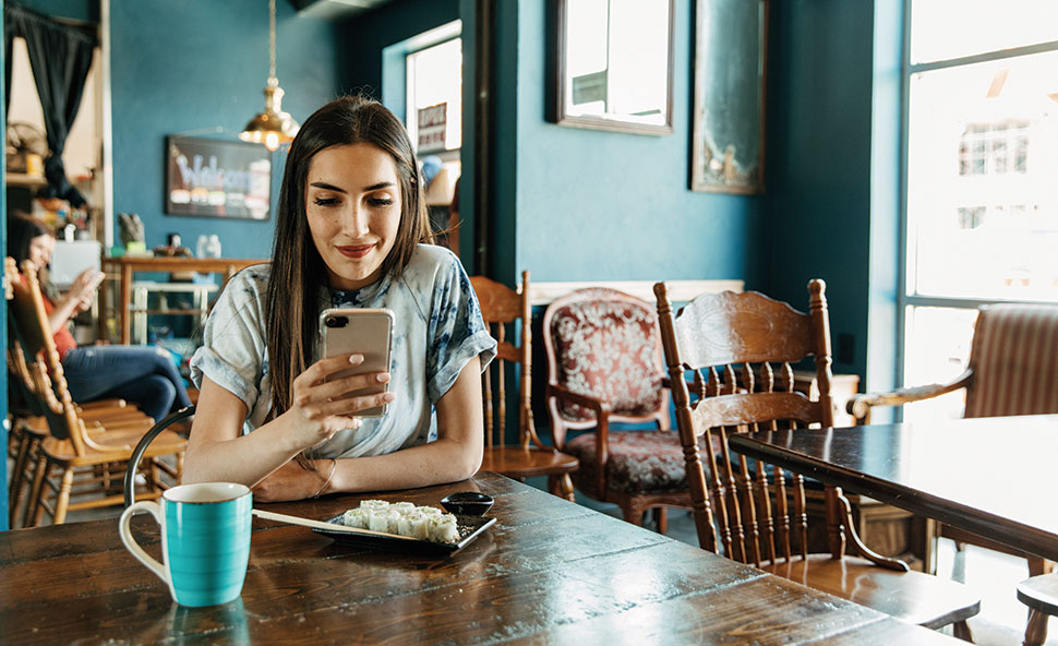 Woman mobile banking on phone at a kitchen table